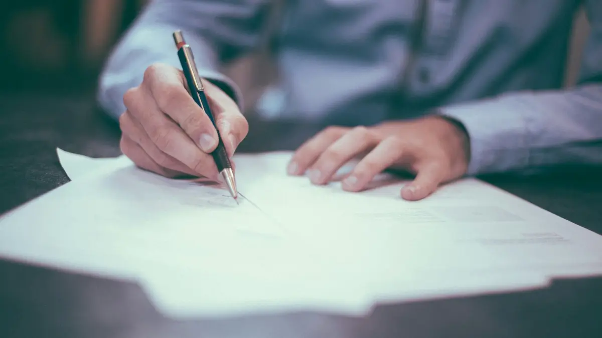 Mãos assinando um documento sobre a mesa